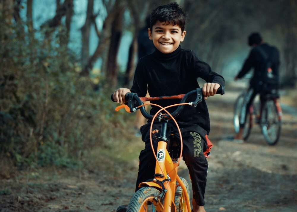 Young boy riding an orange bicycle outdoors